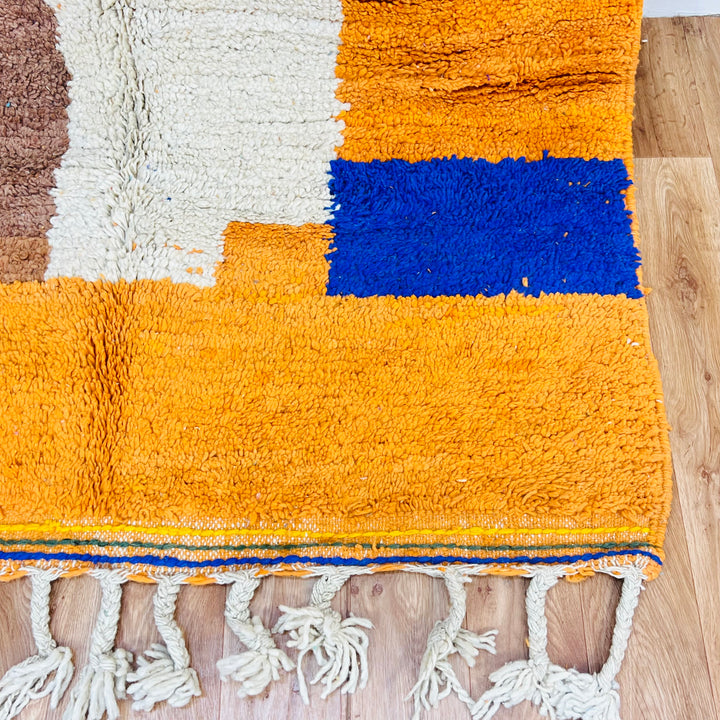 Vibrant Moroccan wool rug with colorful patterns, featuring orange and blue abstract designs, handmade by Berber artisans.
