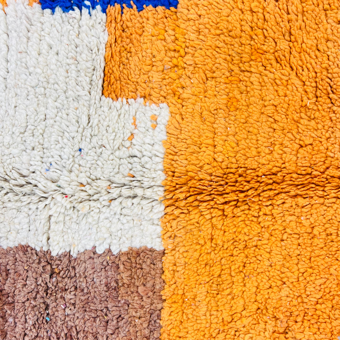 Vibrant Moroccan wool rug in abstract patterns, featuring bold colors like orange, white, and brown. Handmade, vintage Berber design.