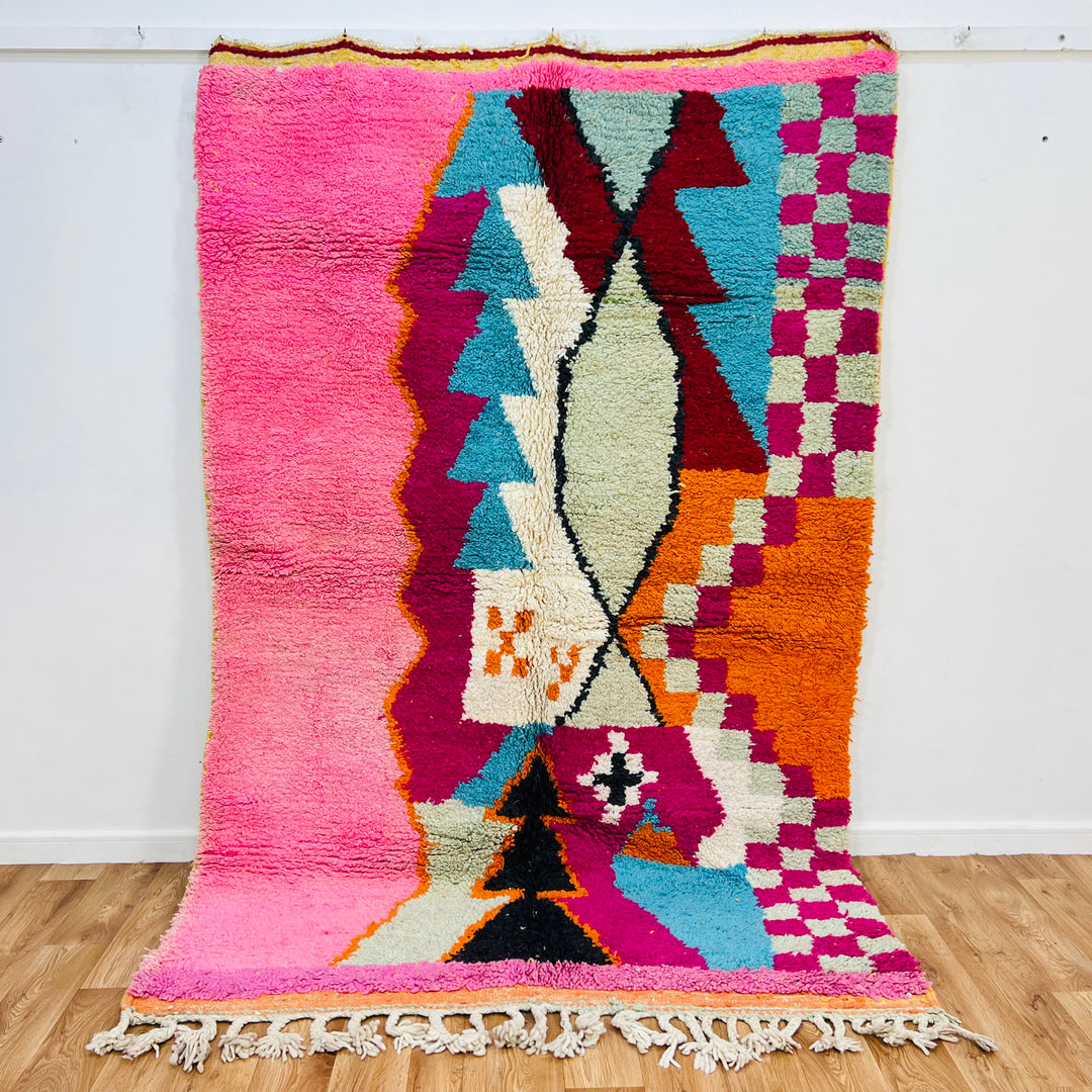 Colorful Moroccan wool rug with bold geometric patterns in pink, teal, and orange, handmade by Berber artisans, 255 × 157 cm.