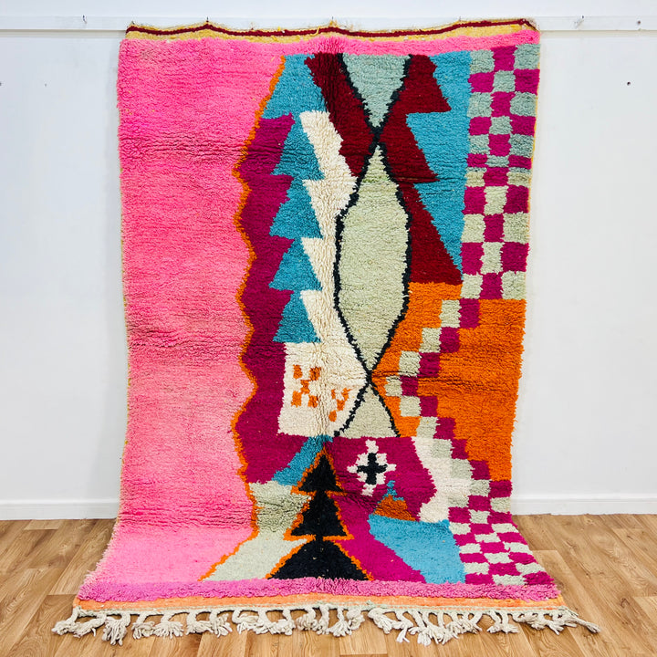 Colorful Moroccan wool rug with bold geometric patterns in pink, teal, and orange, handmade by Berber artisans, 255 × 157 cm.