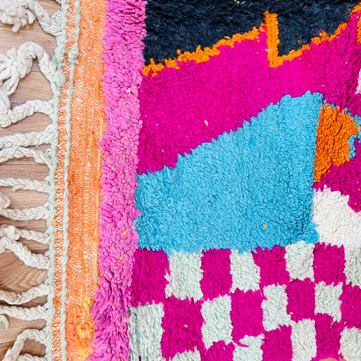 Colorful Moroccan wool rug with pink, blue, and orange patterns, showcasing traditional Berber craftsmanship. Perfect for boho spaces.