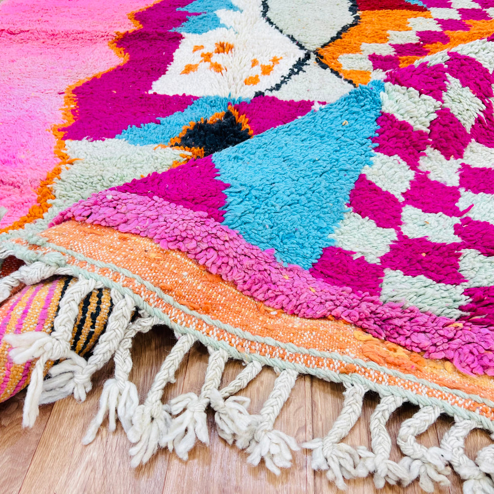 Colorful Moroccan wool rug with pink, aqua, and orange patterns, showcasing traditional Berber design and vibrant boho style.