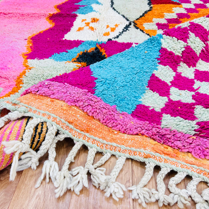 Colorful Moroccan wool rug with pink, aqua, and orange patterns, showcasing traditional Berber design and vibrant boho style.
