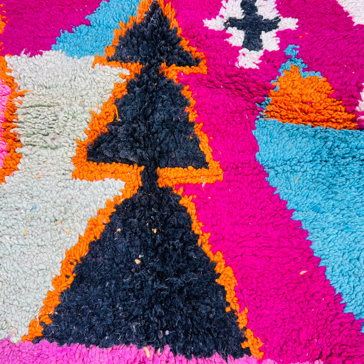 Vibrant Moroccan wool rug with bold colorful stripes in red, pink, blue, and black, handwoven by Berber artisans. Rug detail.