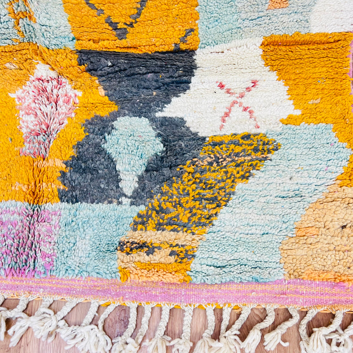 Colorful geometric patterns on handmade vintage Moroccan rug with fringe detail.
