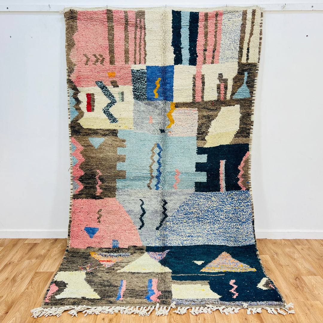 Vintage Moroccan rug with handwoven geometric patterns in pink, blue, and brown, made by Berber women. Dimensions: 278 x 151 cm.