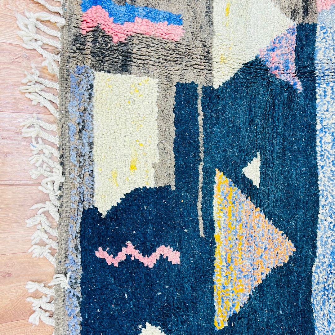 Colorful Vintage Moroccan Rug with geometric patterns in fuchsia, mustard yellow, and sky blue on wooden floor, 278 x 151 cm.
