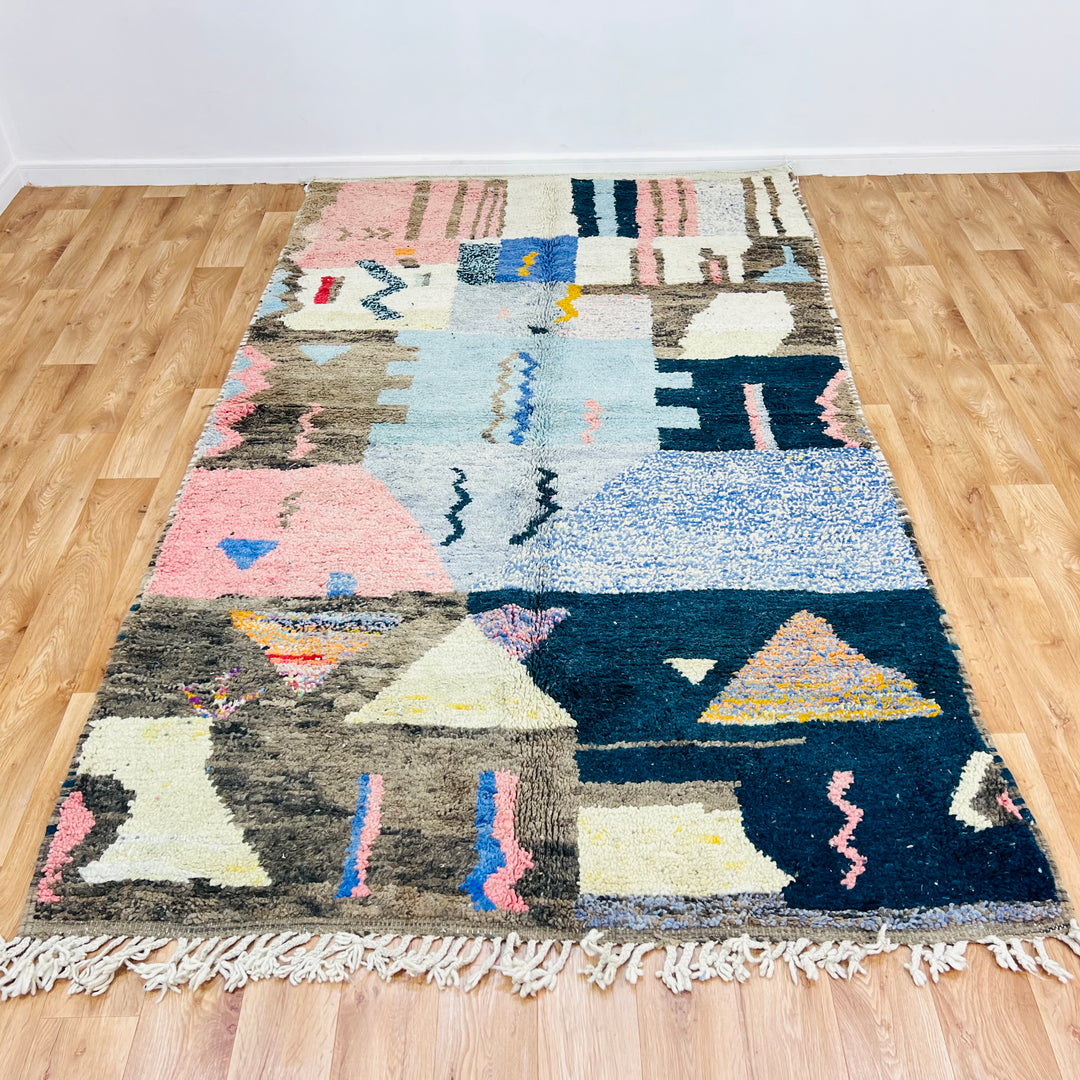 Colorful vintage Moroccan rug with fuchsia, mustard, and blue motifs on a wool texture; traditional Berber craftsmanship.