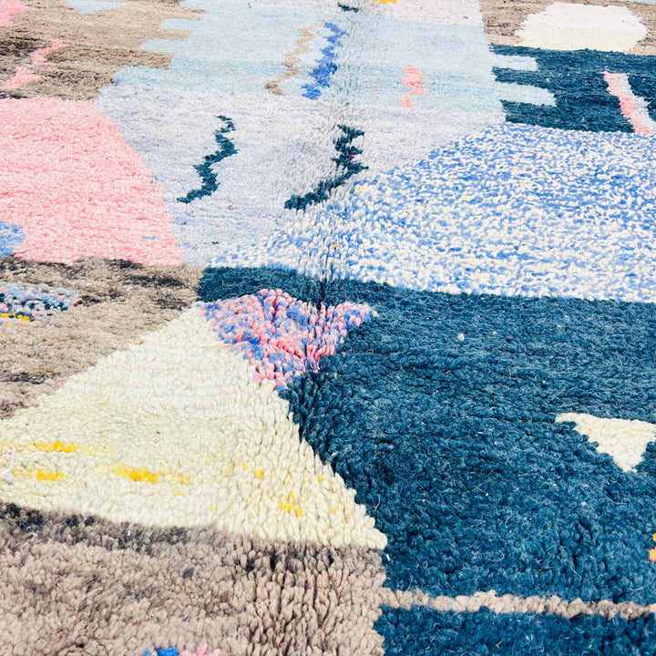 Close-up of a colorful Vintage Moroccan Rug with geometric shapes in blue, pink, and yellow. Handwoven Berber wool rug.