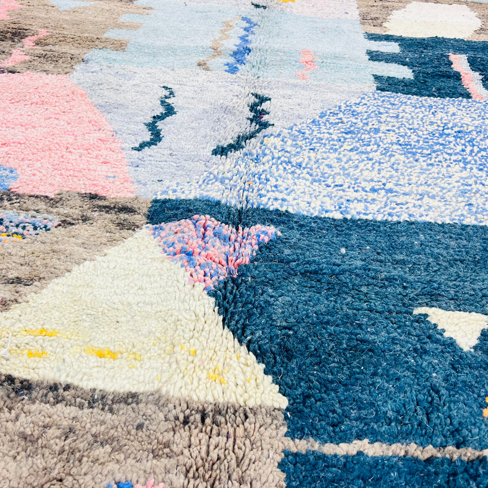 Close-up of a colorful Vintage Moroccan Rug with geometric shapes in blue, pink, and yellow. Handwoven Berber wool rug.