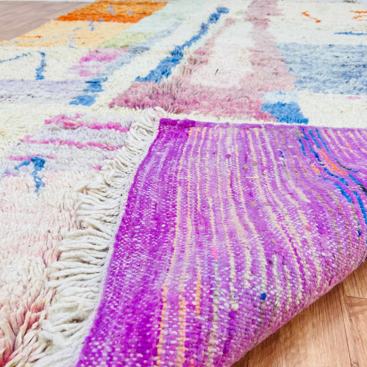 Pastel Moroccan wool rug with abstract design and colorful fringes, handmade by Berber artisans. Area rug for boho interiors.