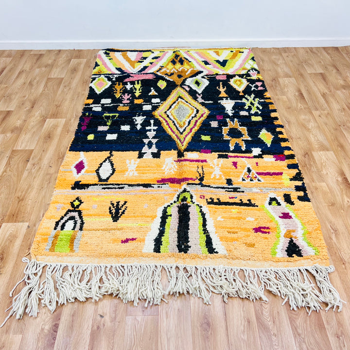 Colorful Moroccan wool rug with diamond and tribal patterns, featuring saffron, fuchsia, lime, and black. Handmade by Berber artisans.