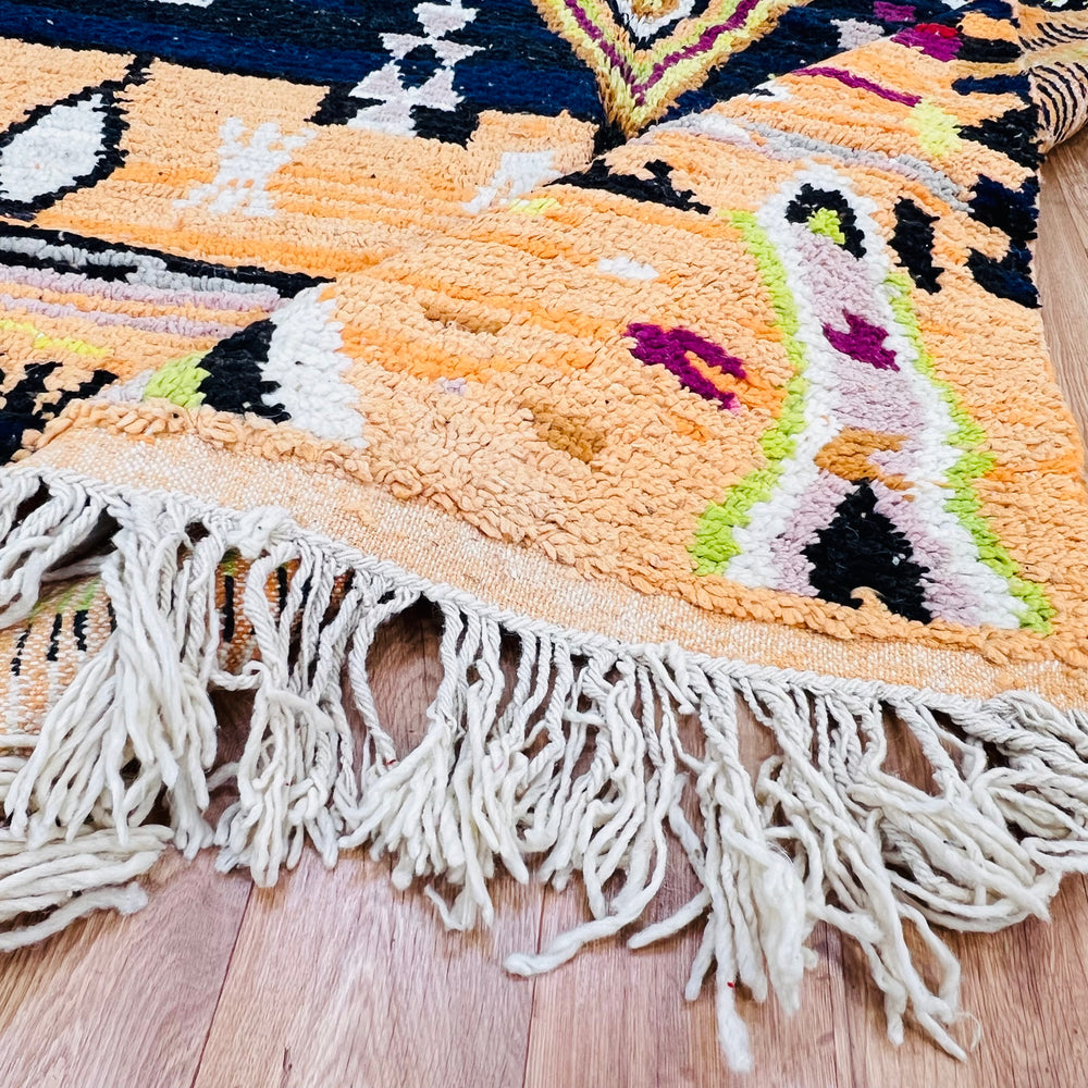Handwoven Moroccan wool rug with tribal design in saffron, fuchsia, lime green, and black; Berber craftsmanship and natural fringe.