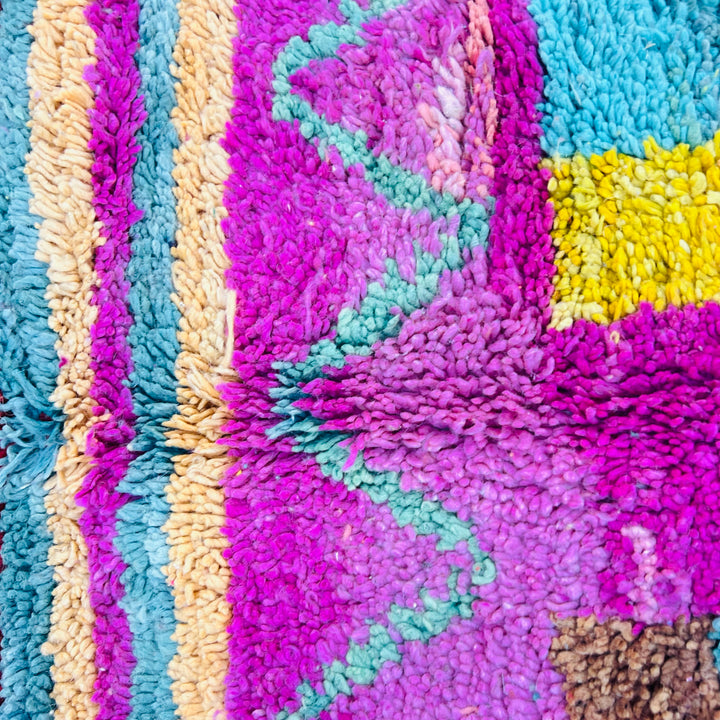 Colorful handmade Moroccan Berber wool rug with vibrant geometric patterns and rich hues.