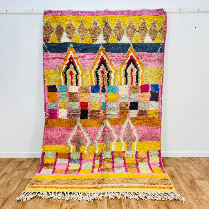 Colorful Moroccan wool rug with diamond and arch motifs, 260 x 158 cm, featuring pink, yellow, and natural tones.