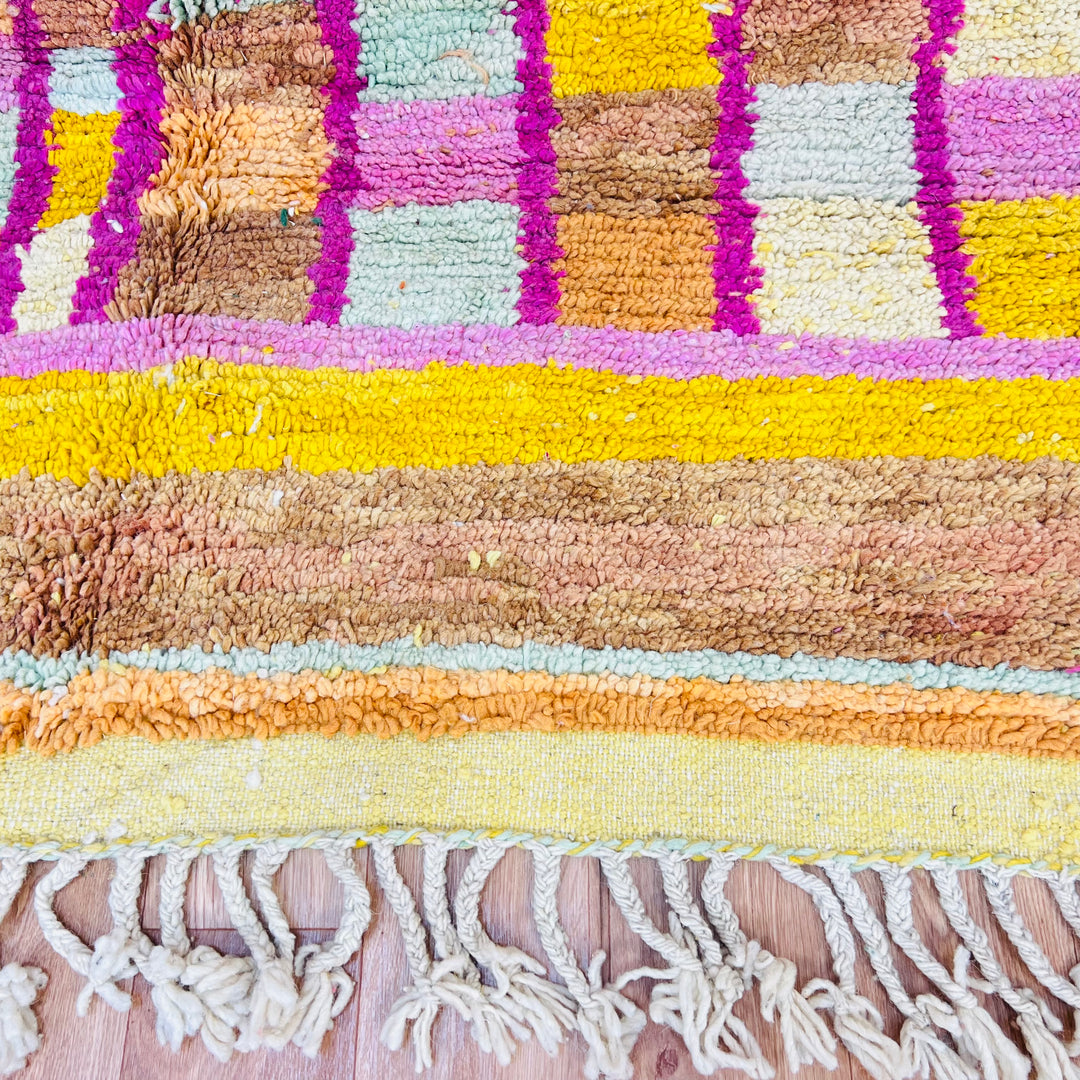 Colorful Moroccan wool rug with yellow, pink, and orange geometric patterns, showcasing traditional Berber design.