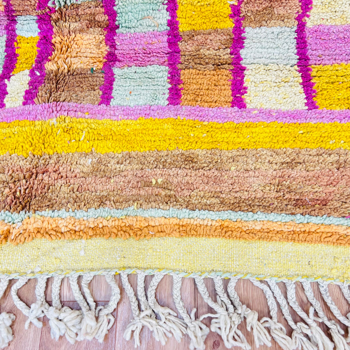 Colorful Moroccan wool rug with yellow, pink, and orange geometric patterns, showcasing traditional Berber design.