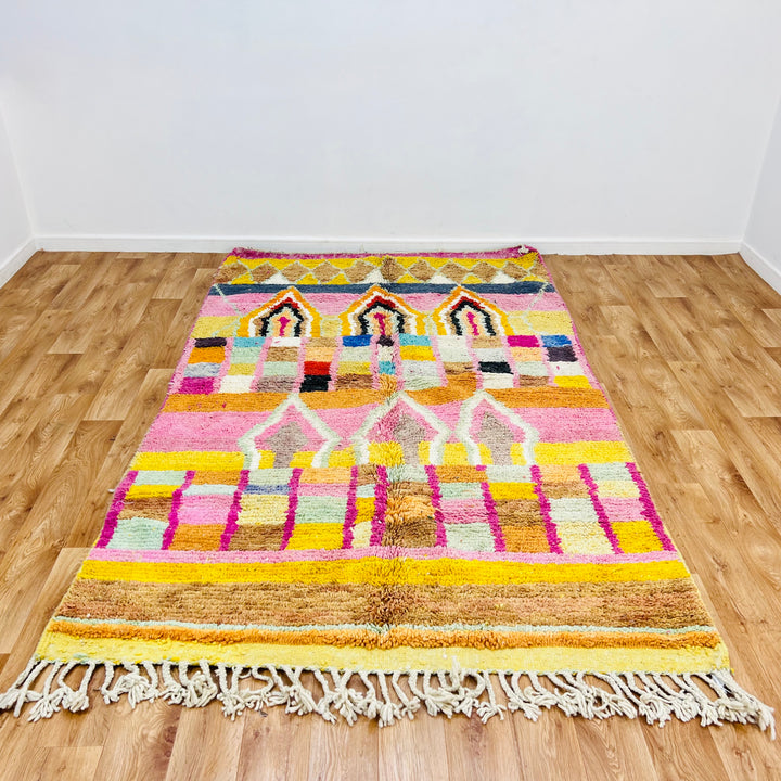 Colorful Moroccan wool rug with diamond and arch motifs, pink, yellow, orange tones. Handmade Berber tradition, 260 x 158 cm.
