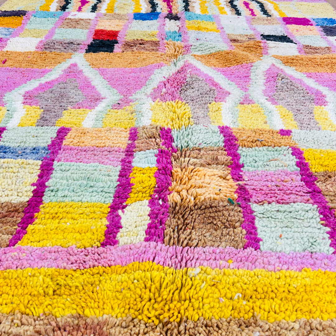 Colorful handmade Moroccan wool rug with geometric patterns in pink, yellow, and orange for vibrant home decor.