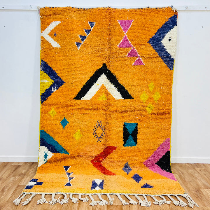 Orange Moroccan Wool Rug with Berber motifs, 246x167 cm, featuring geometric patterns in black, pink, blue, red, yellow, ivory.