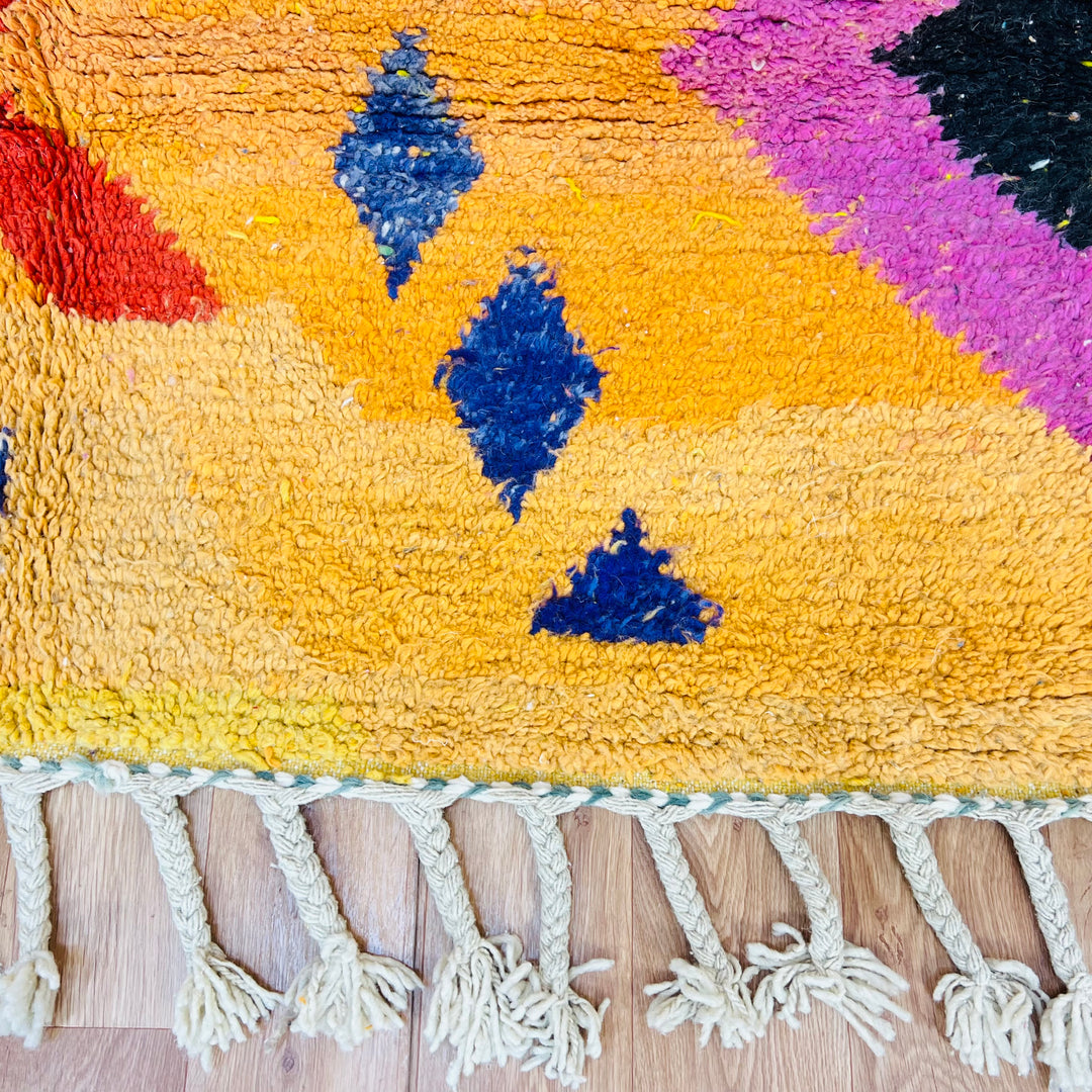 Orange Moroccan wool rug with tribal Berber motifs in black, pink, and blue. Handmade, textured wool surface. Size: 246x167 cm.