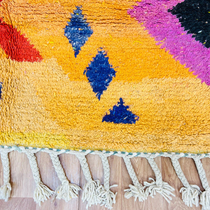 Orange Moroccan wool rug with tribal Berber motifs in black, pink, and blue. Handmade, textured wool surface. Size: 246x167 cm.