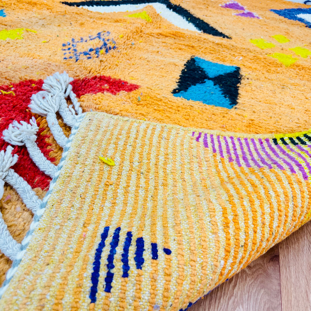 Handmade orange Moroccan wool rug with tribal Berber motifs and vibrant colors. Perfect for modern and bohemian spaces.
