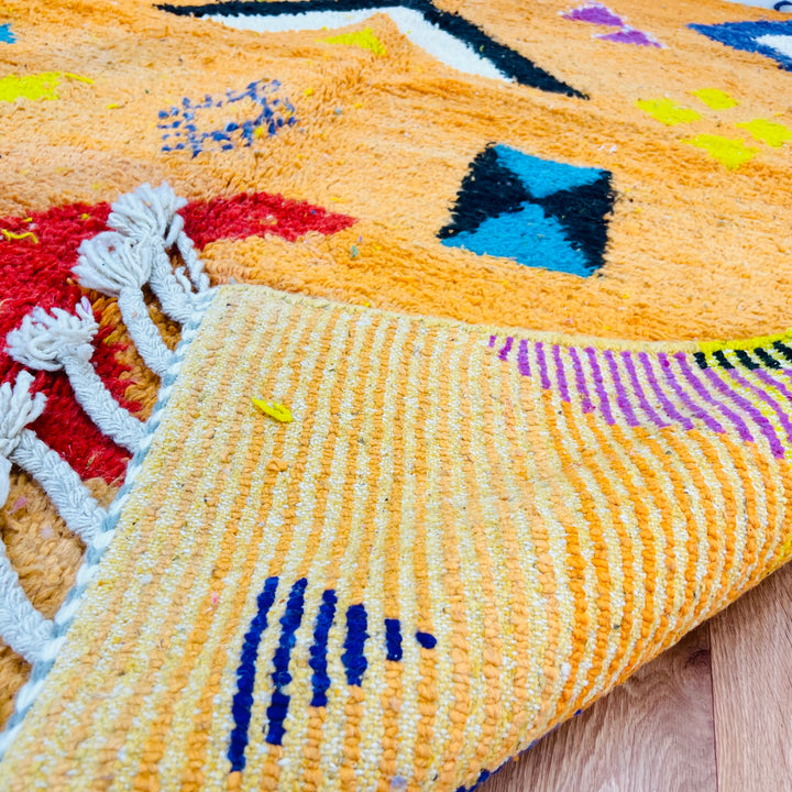 Handmade orange Moroccan wool rug with tribal Berber motifs and vibrant colors. Perfect for modern and bohemian spaces.