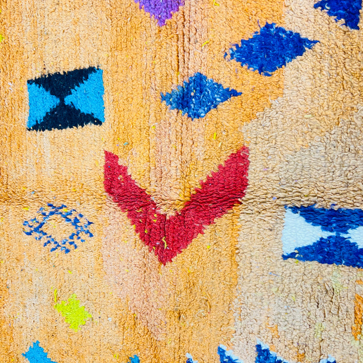 Orange Moroccan wool rug with Berber motifs in blue, red, pink, and black. Traditional Amazigh artistry, handwoven 246x167 cm.
