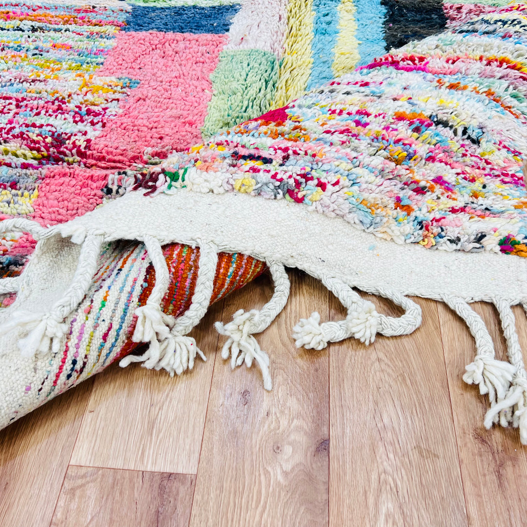 Colorful Moroccan Berber Wool Rug with vibrant abstract patterns and tassels, showcasing traditional craftsmanship on wooden floor.