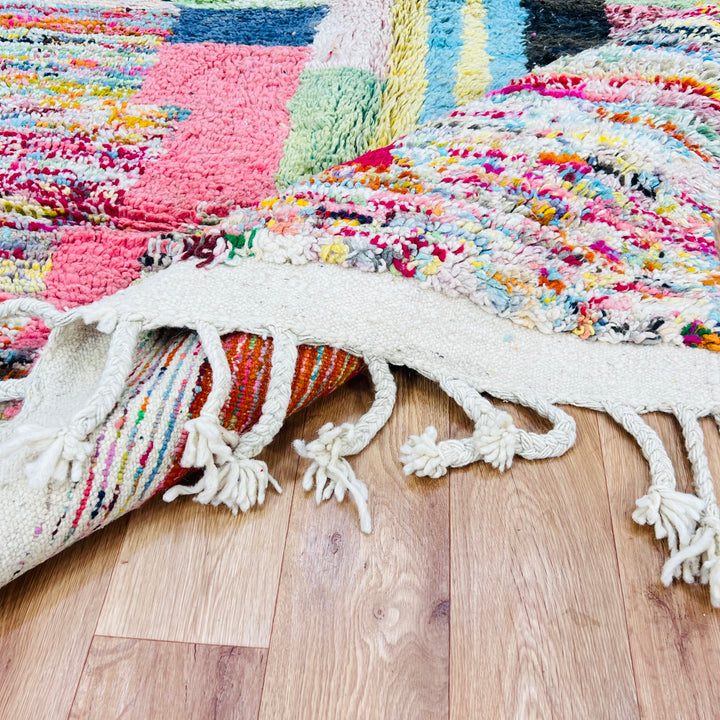 Colorful Moroccan Berber Wool Rug with vibrant abstract patterns and tassels, showcasing traditional craftsmanship on wooden floor.