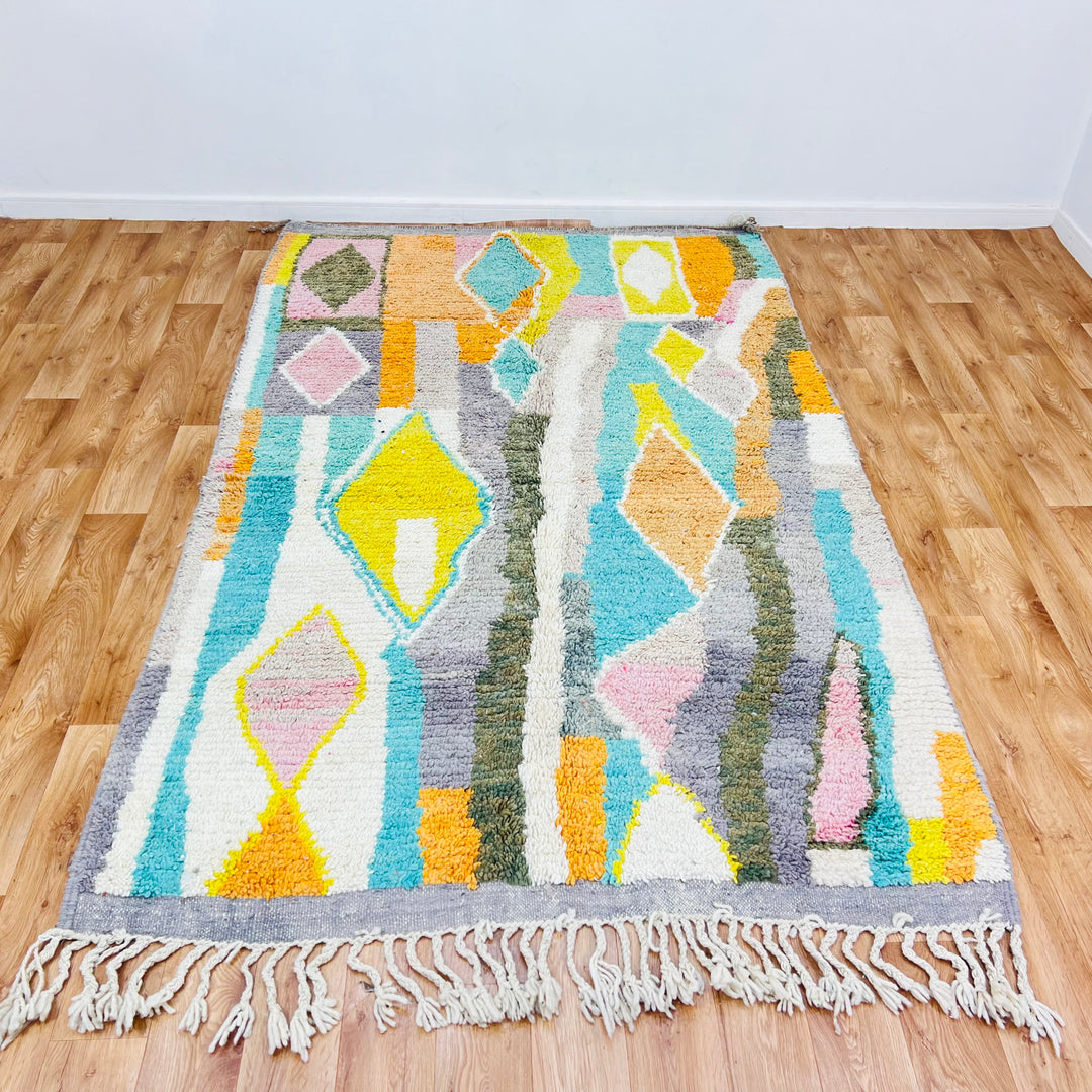 Colorful Moroccan wool rug with diamond patterns in orange, teal, yellow, and blush pink, 264x160 cm. Traditional Berber design.