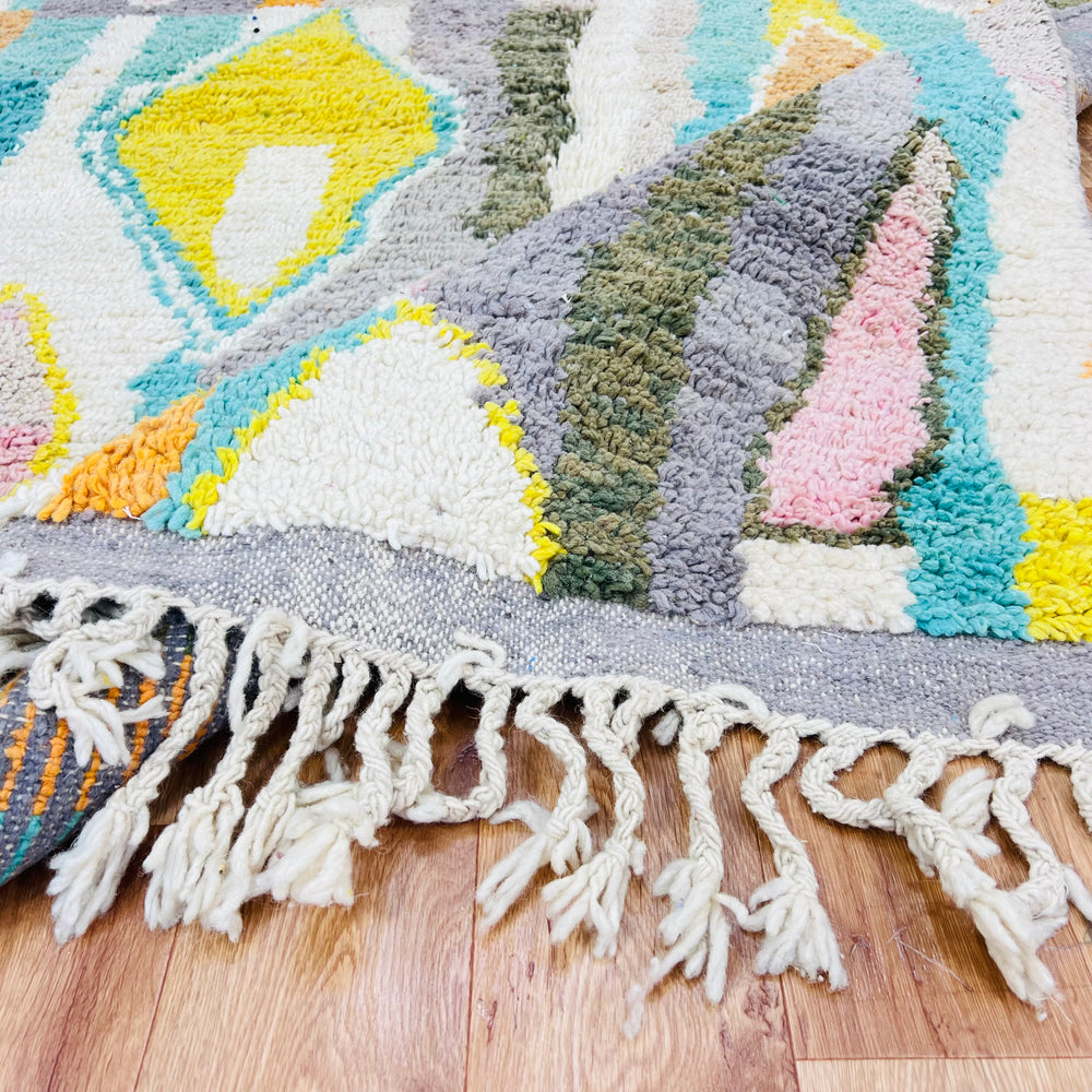 Colorful diamond Moroccan wool rug with fringe, featuring vibrant orange, teal, yellow, and blush pink patterns. Size 8.6 x 5 ft.