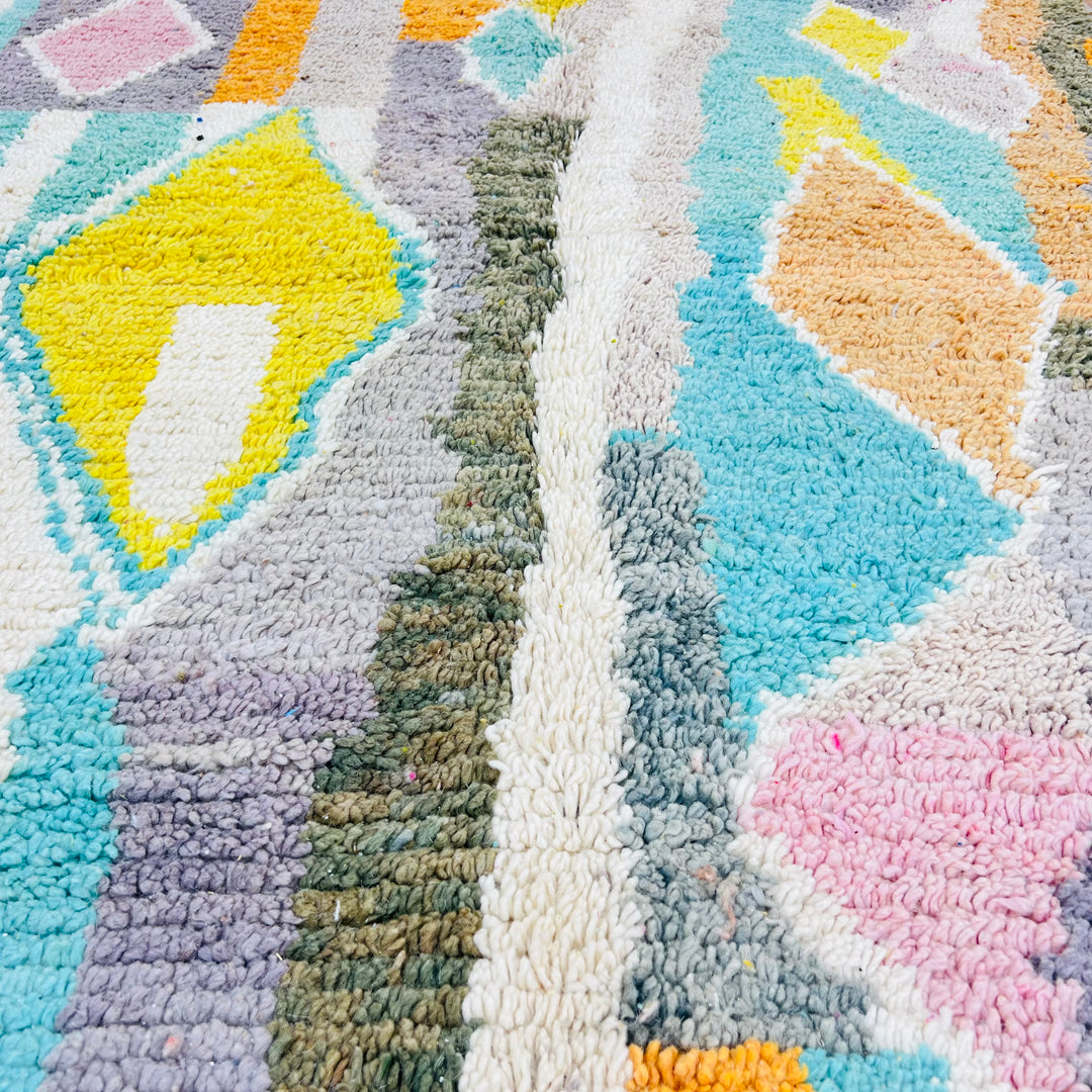 Colorful Moroccan wool rug with diamond patterns in teal, orange, yellow, and pink. Handmade using traditional Berber techniques.