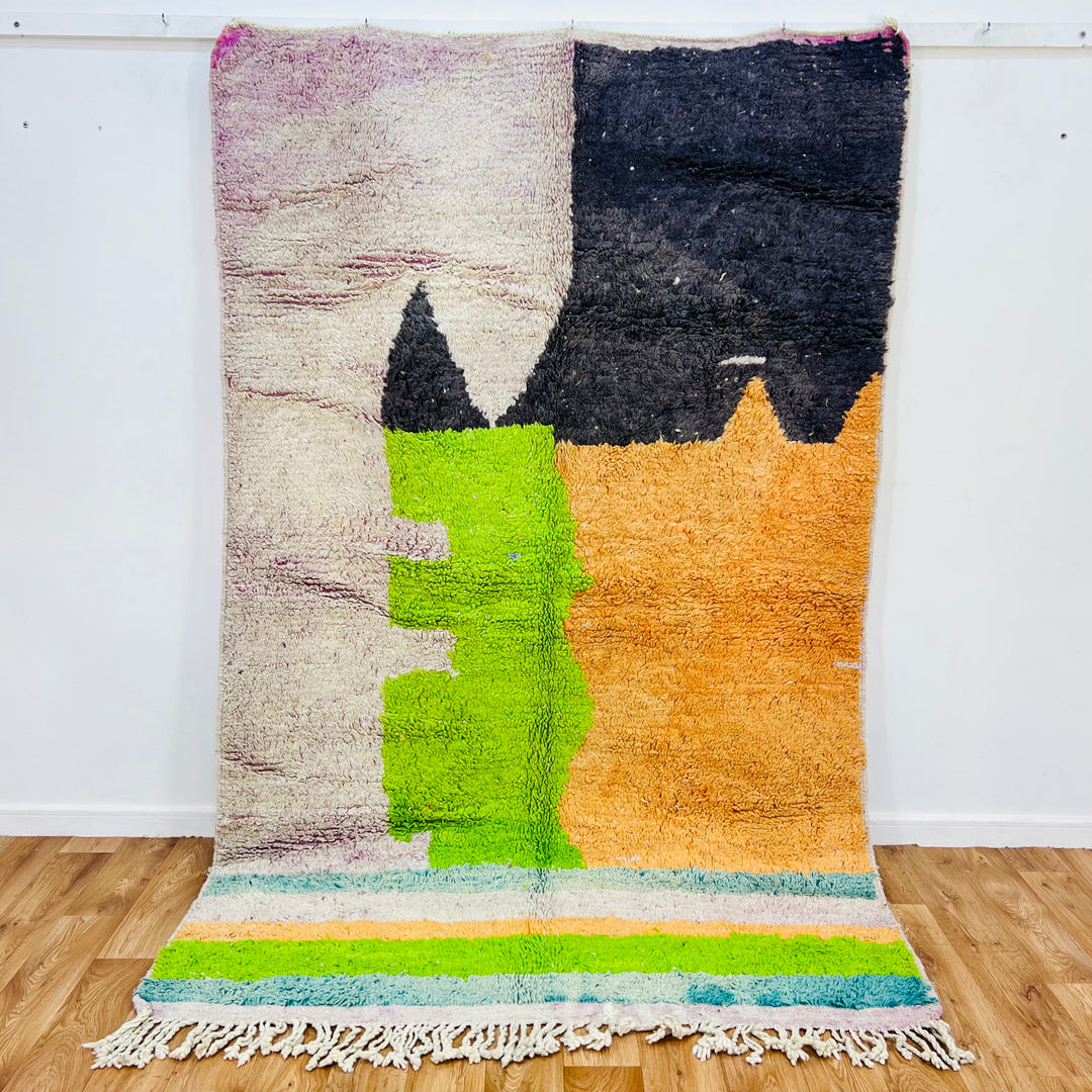 Handmade Moroccan wool rug with bold geometric color blocks in black, orange, lime green, and ivory, 260 x 163 cm.