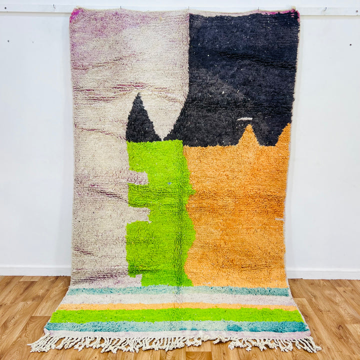 Handmade Moroccan wool rug with bold geometric color blocks in black, orange, lime green, and ivory, 260 x 163 cm.