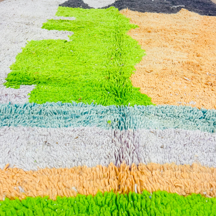 Handmade Moroccan wool rug with vibrant black, orange, lime green, and ivory color blocks, designed in geometric shapes.