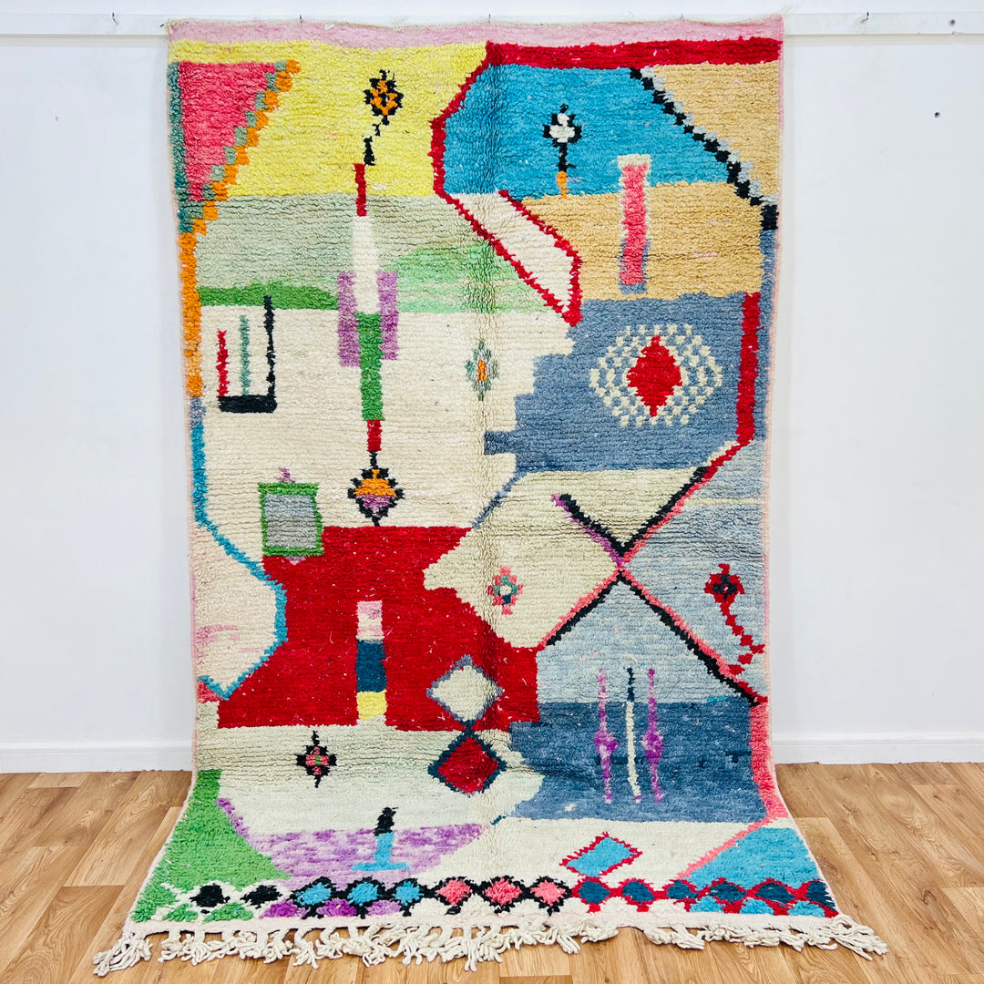 Colorful Moroccan Berber rug with geometric patterns, featuring bold reds, blues, greens, and pastels. Handmade 256x157 cm.