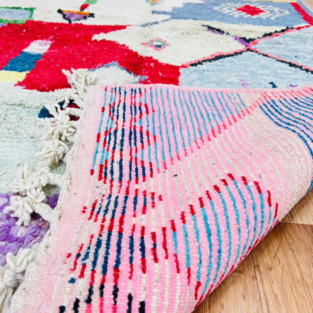 Colorful Moroccan Berber rug with geometric patterns, showcasing red, blue, and pastel colors. Handmade traditional design.