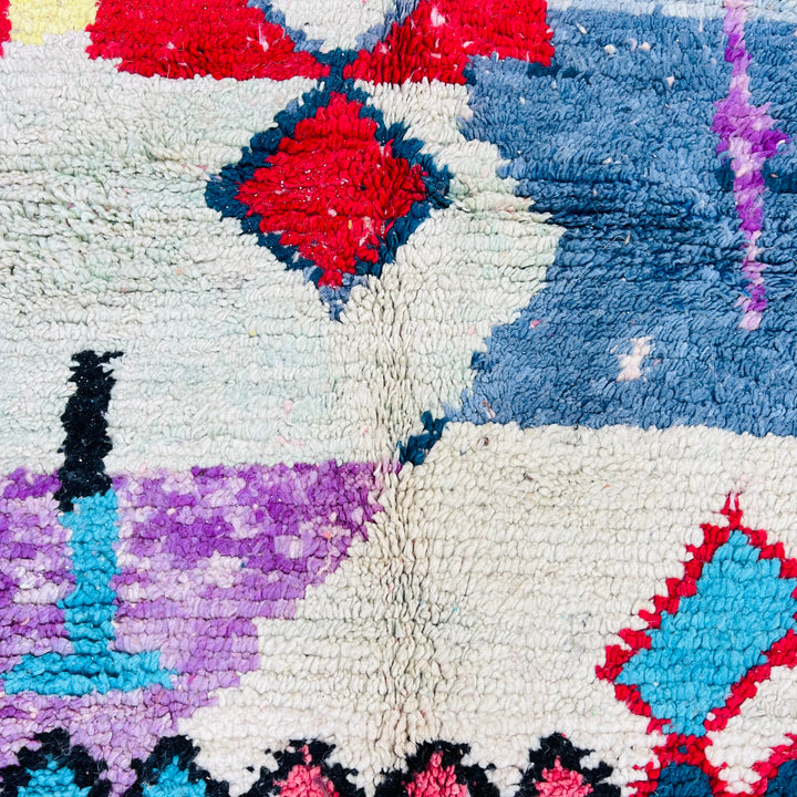 Colorful Moroccan Berber rug with geometric patterns in red, blue, and pastels, handmade vintage style. Perfect for boho interiors.