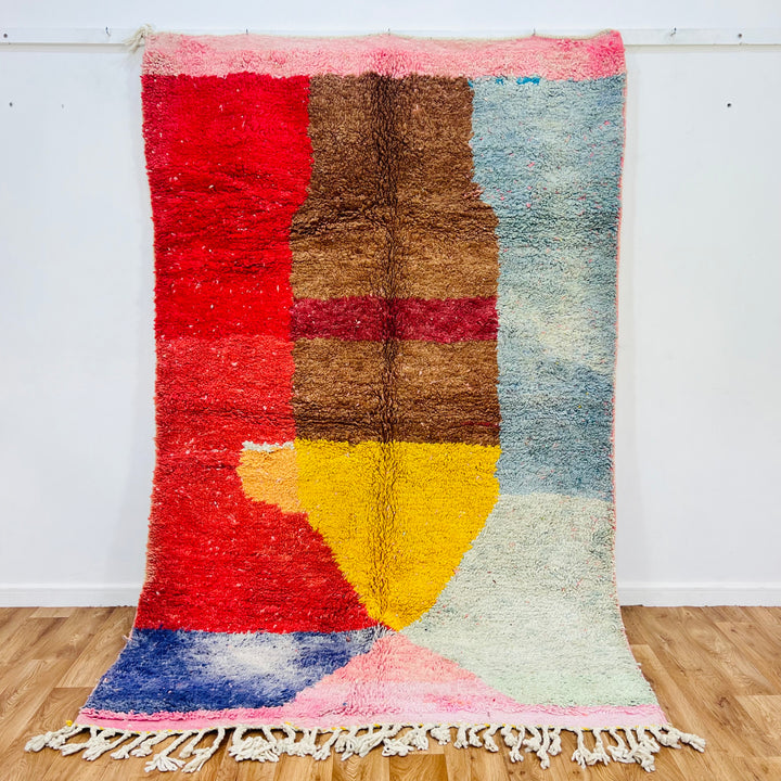 Vintage Moroccan rug with colorful geometric patterns on a wooden floor.