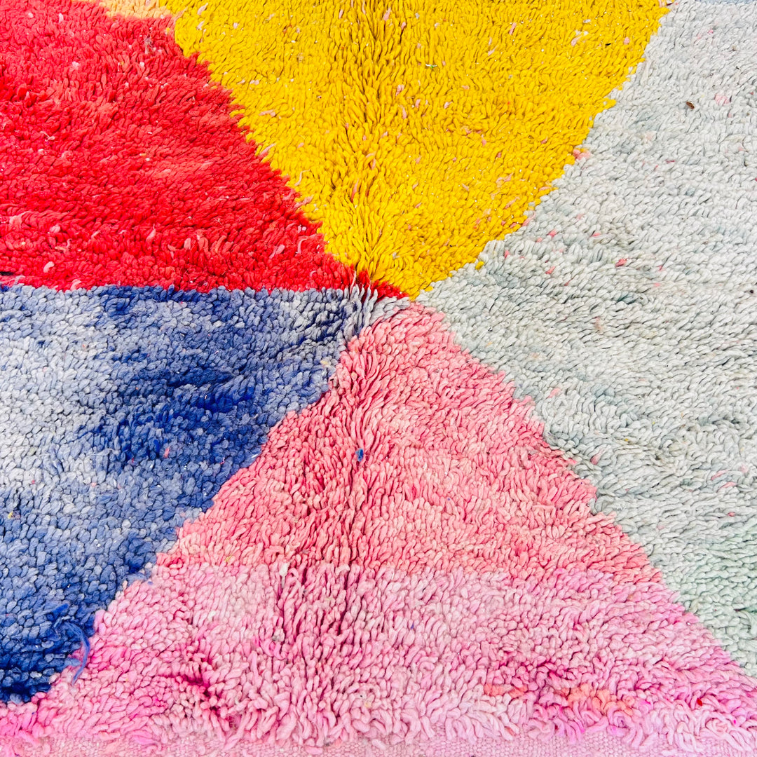 Colorful vintage Moroccan rug texture with pink, yellow, blue, and gray sections, displaying intricate wool craftsmanship.