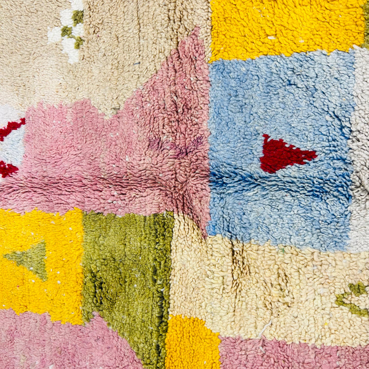 Colorful vintage Moroccan wool rug with pink, blue, yellow, and green patchwork design, handwoven in the Atlas Mountains.