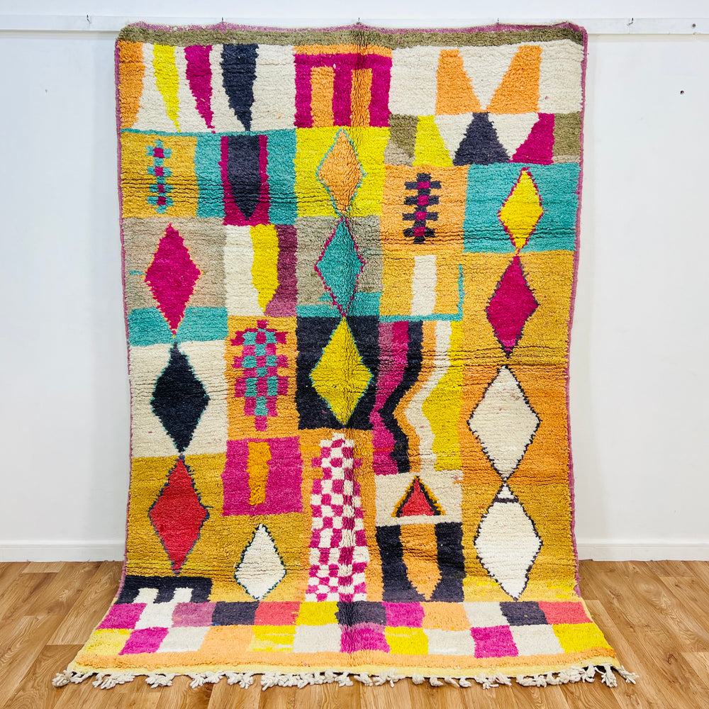 Colorful handmade Beni Mrirt Moroccan rug with vibrant diamond and checkerboard patterns in pink, yellow, black, and teal.