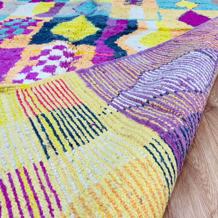 Colorful Beni Mrirt Moroccan rug with geometric motifs in pink, yellow, black, and teal, handmade from soft wool, 251 x 164 cm.