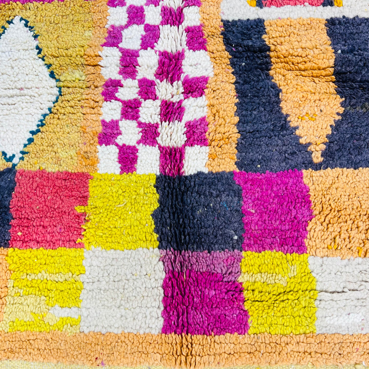 Colorful Beni Mrirt Moroccan rug with diamond and checkerboard patterns in pink, yellow, black, and teal shades. Handmade wool rug.