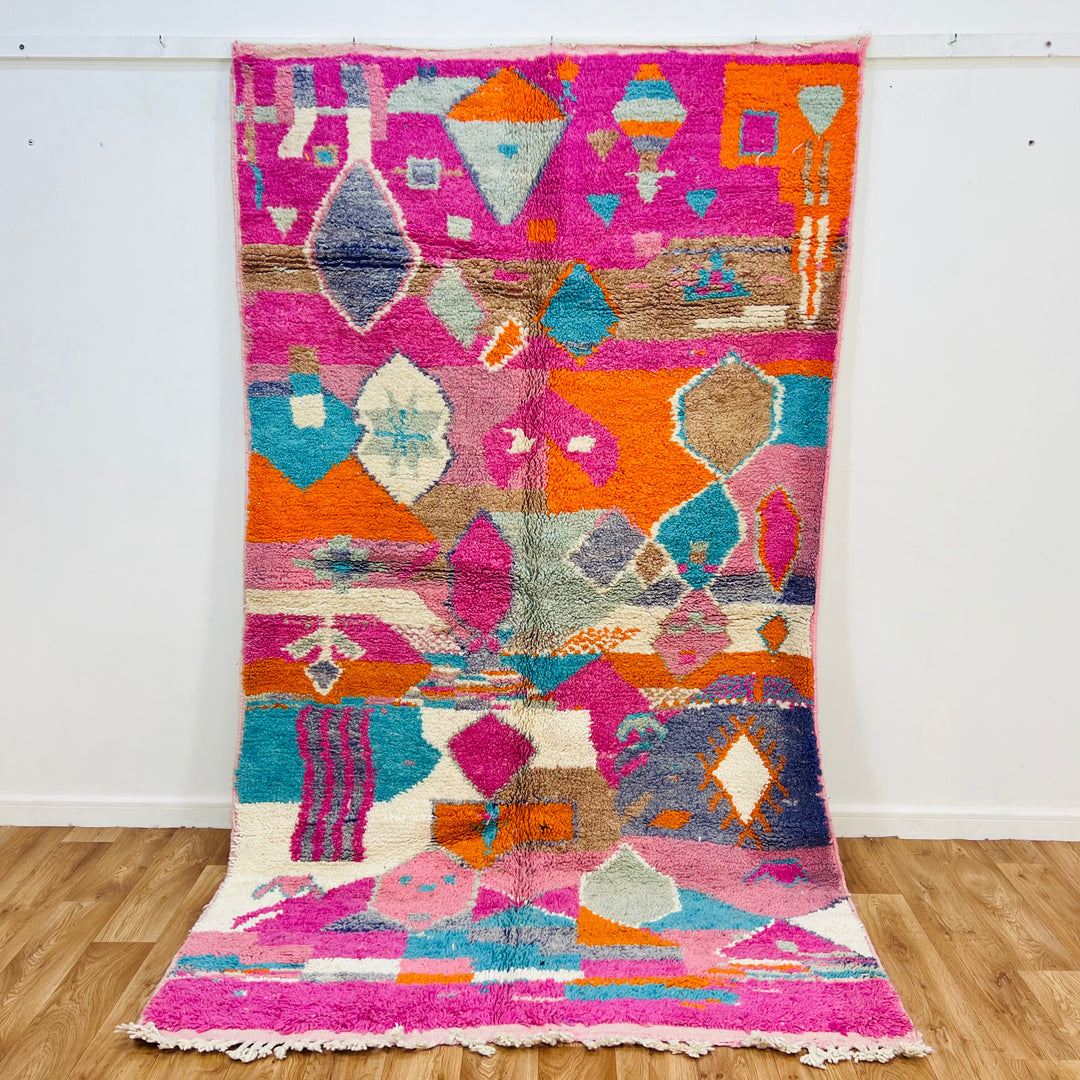 Vibrant handmade Moroccan wool rug with geometric patterns in pink, orange, turquoise, and cream, 266x153 cm.