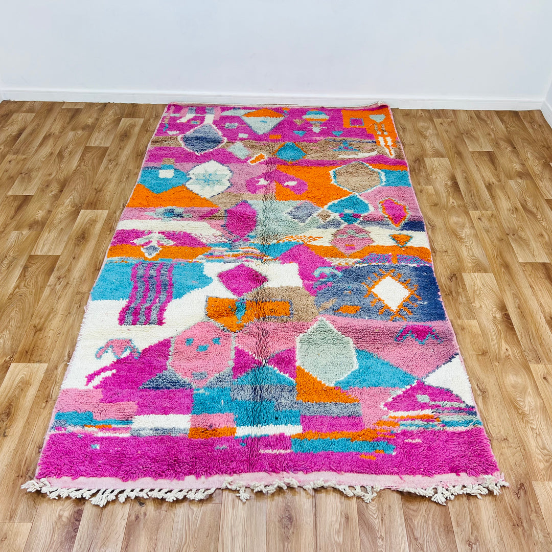 Colorful Moroccan wool rug with pink, orange, and blue geometric patterns, handmade by Berber artisans. Size: 266 x 153 cm.