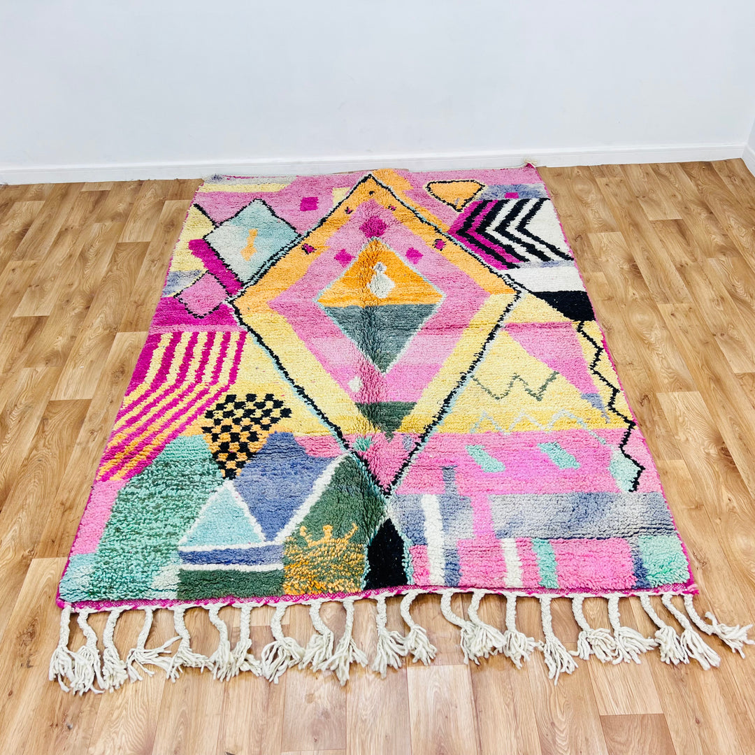 Pink Diamond Moroccan wool rug with colorful geometric patterns on wooden floor, handmade by Berber women. Size: 234x164 cm.
