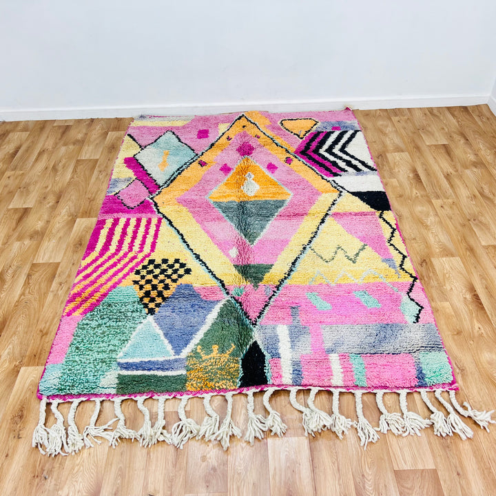 Pink Diamond Moroccan wool rug with colorful geometric patterns on wooden floor, handmade by Berber women. Size: 234x164 cm.